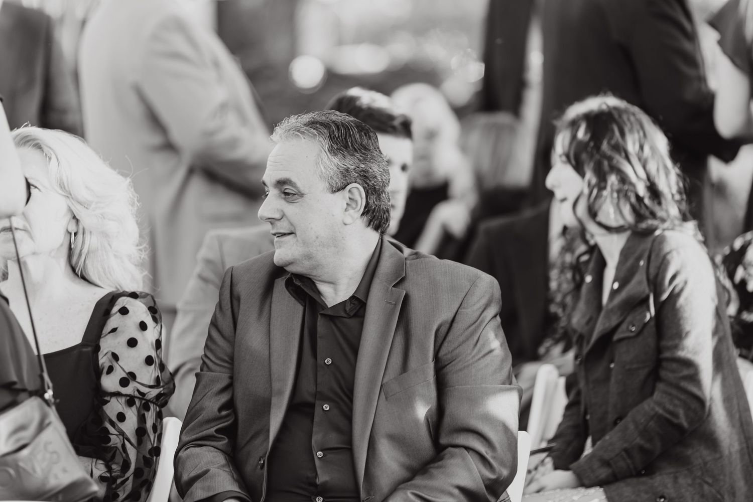Black and white candid photo of guests enjoying an outdoor celebration.