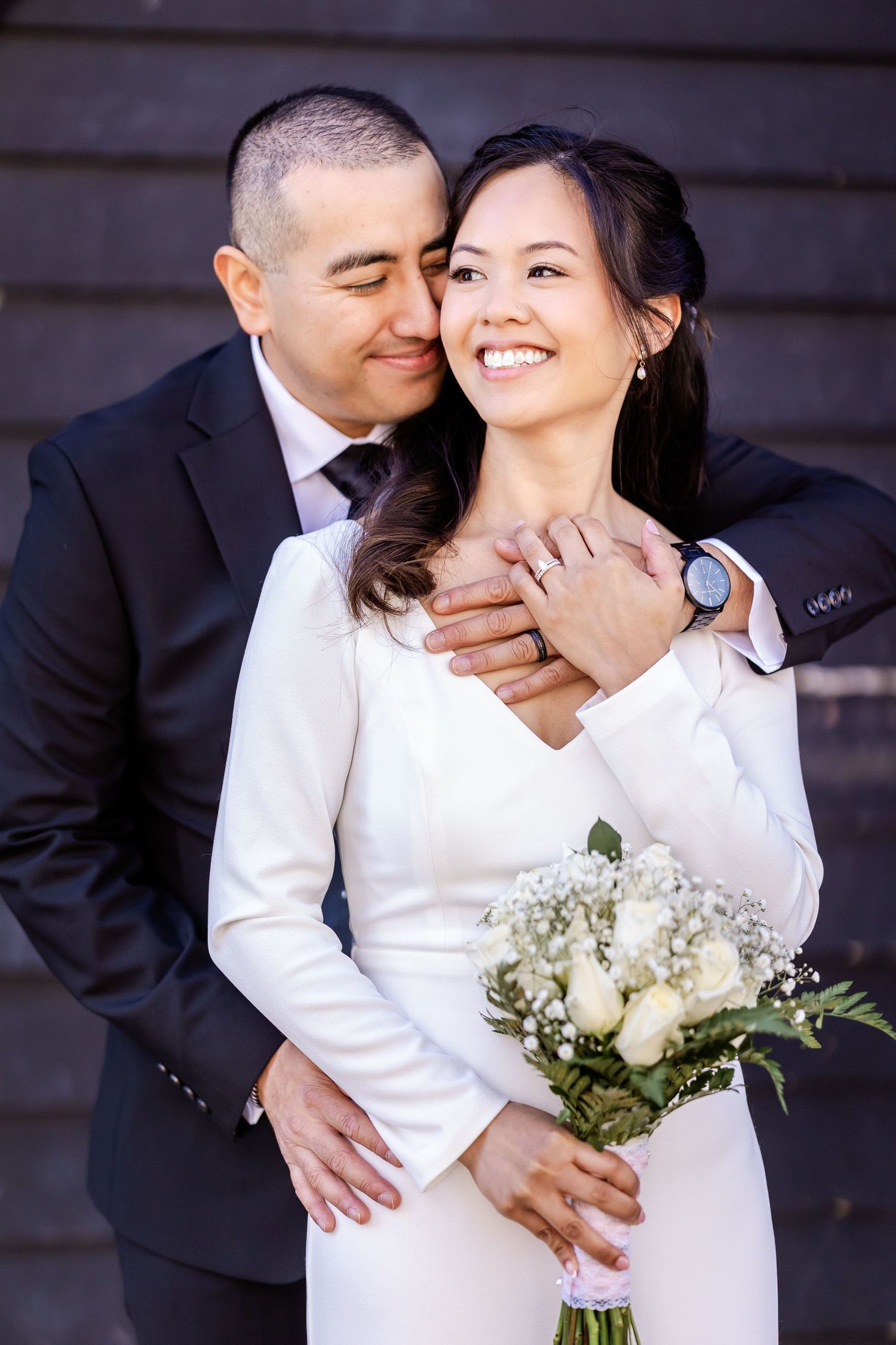 An intimate wedding portrait showing a tender embrace and joyful smiles.