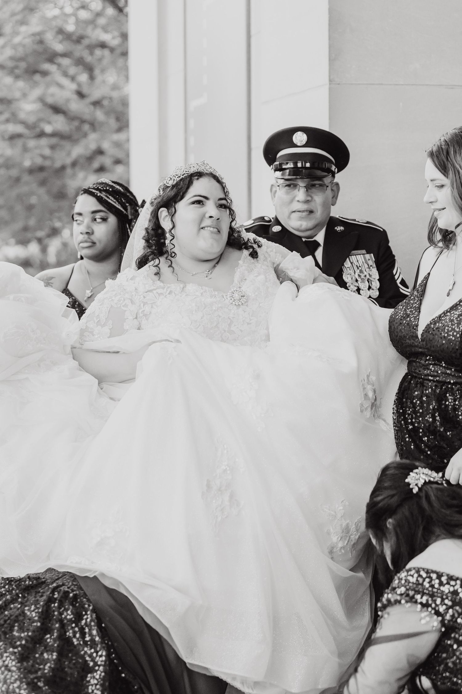 Wedding party in formal attire sits together in black and white photograph.