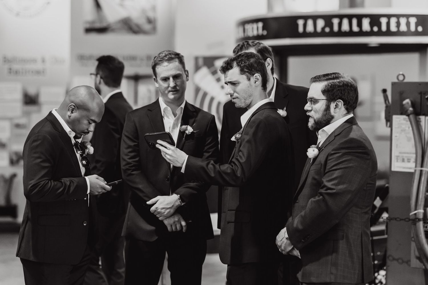 A black and white photo of groomsmen gathered in conversation before the ceremony.
