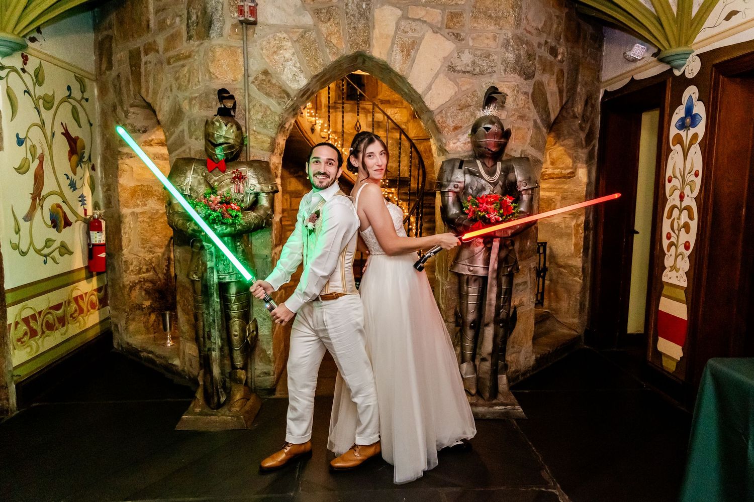 Star Wars themed wedding celebration with lightsabers glowing in green and red against stone wall backdrop.