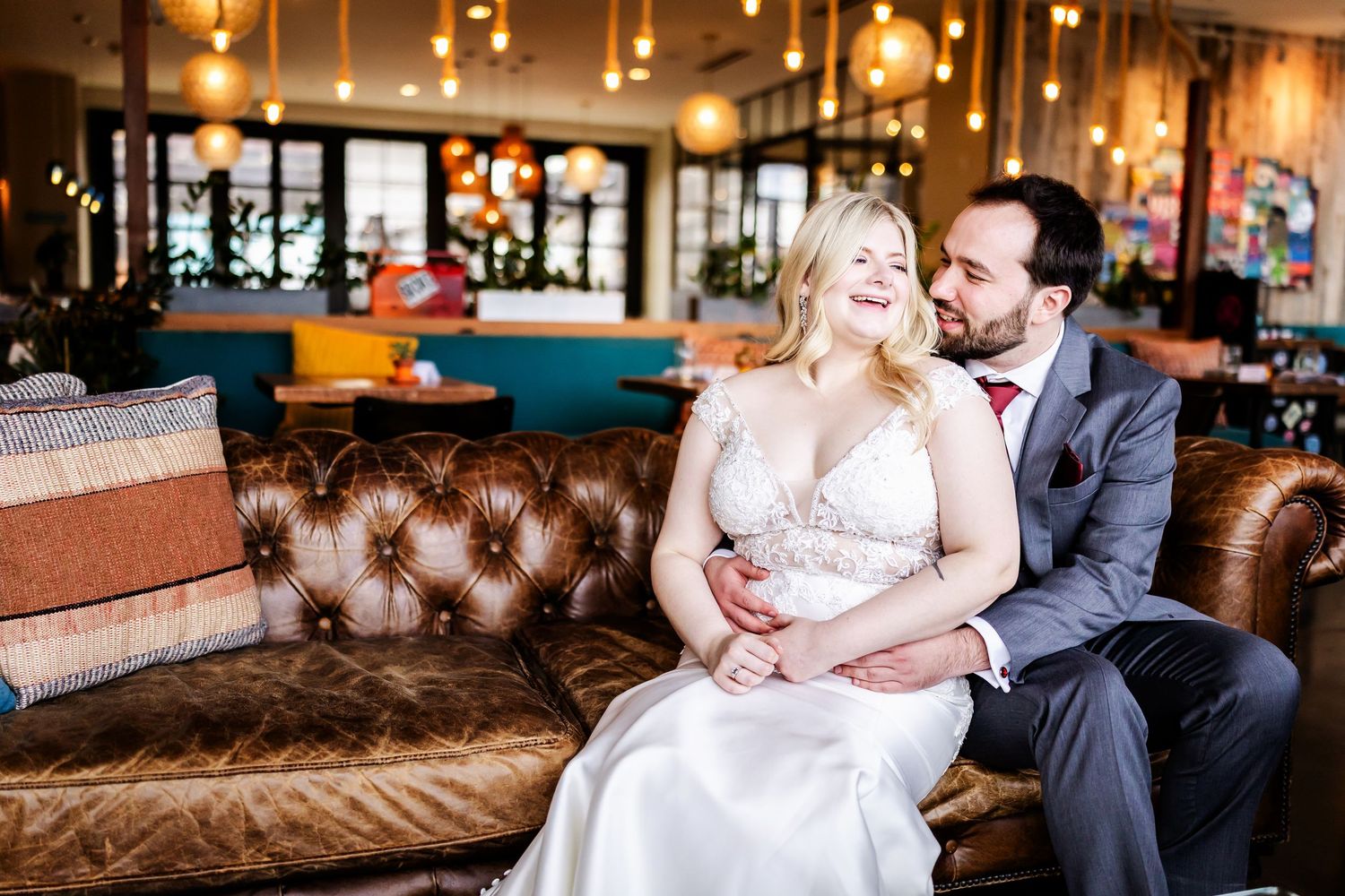 Romantic couple shares intimate moments together on brown leather couch in cozy indoor setting with warm lighting.
