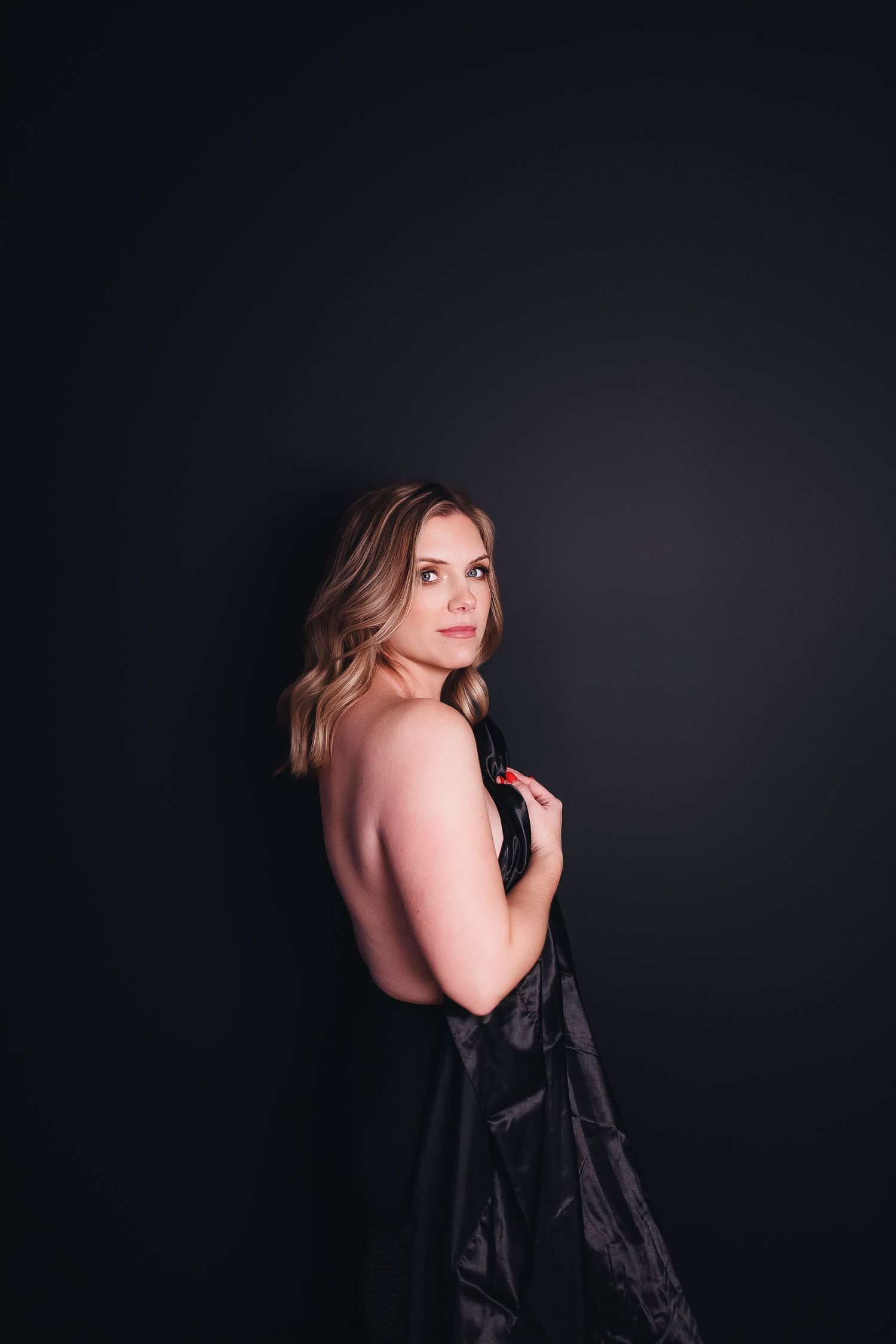 Dramatic dark studio portraits showing artistic poses in black dress.