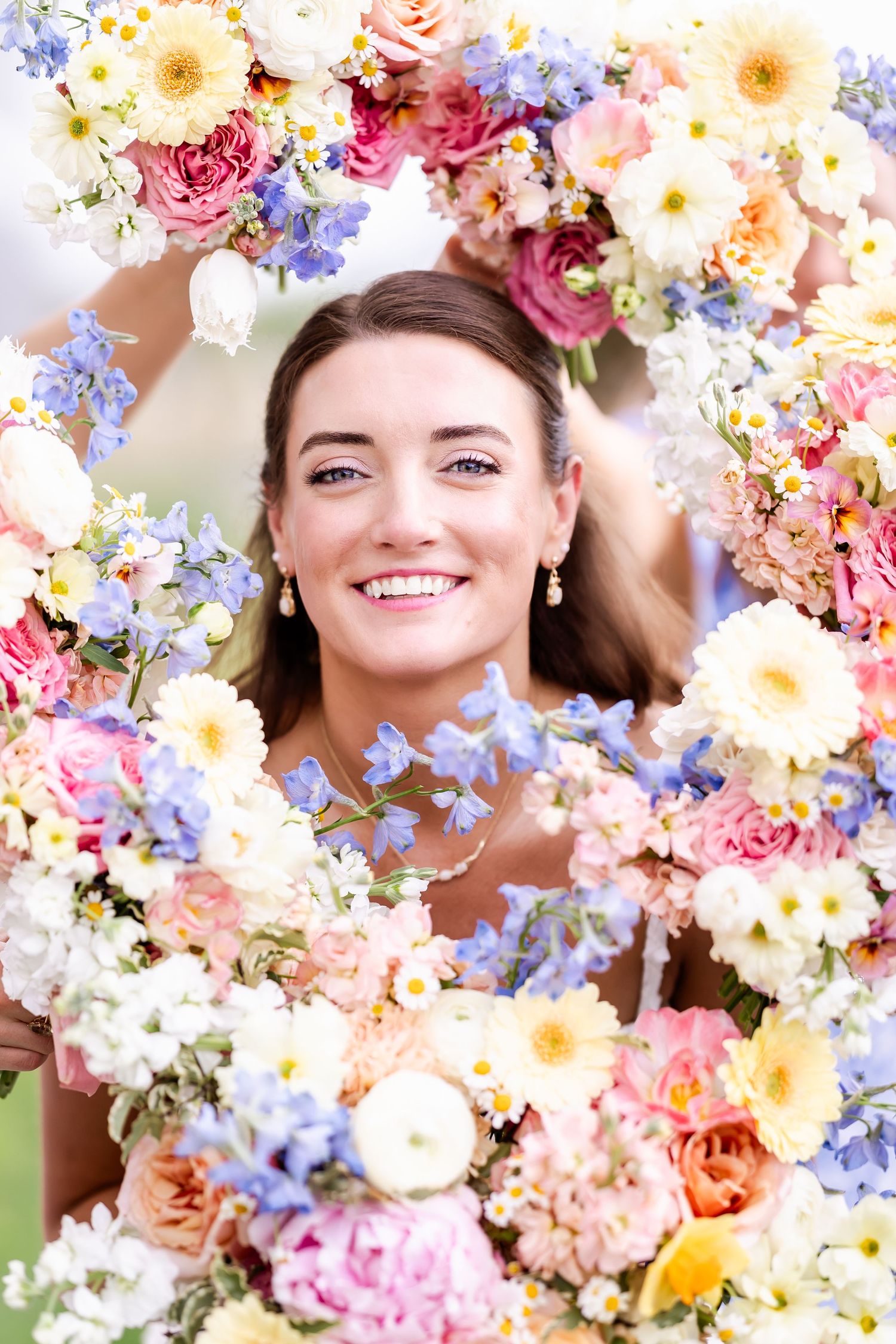 Colorful spring wedding flowers featuring roses, daisies and blue delphinium in a romantic arrangement.