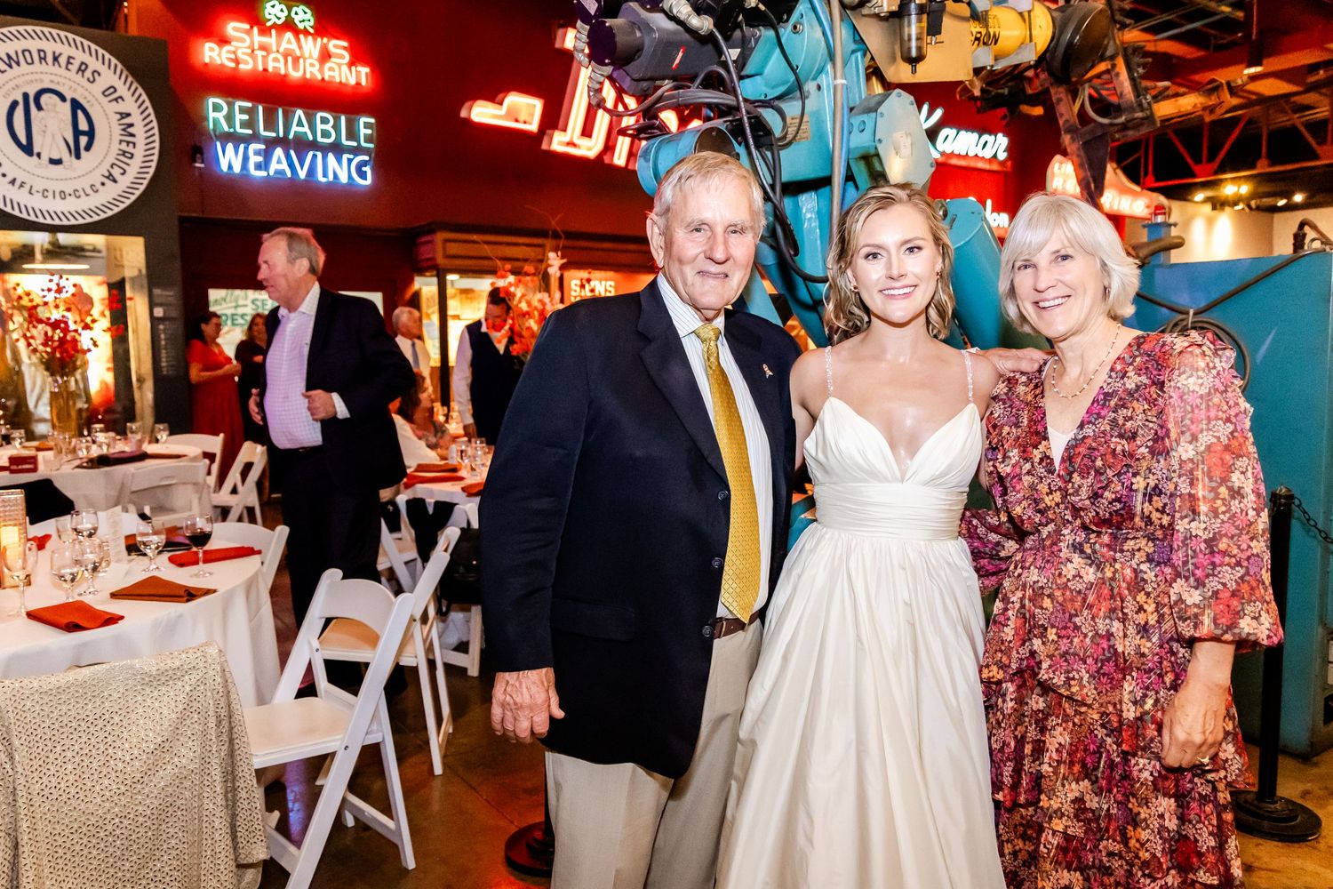 A wedding celebration taking place in a rustic indoor venue with decorative lighting and table settings.
