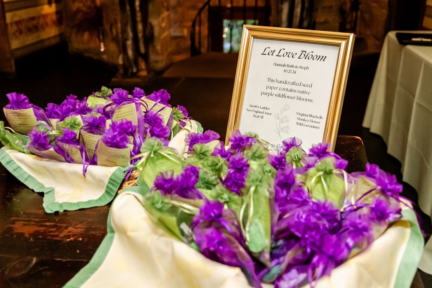 Purple orchid flowers arranged with greenery alongside a framed sign on a dark wooden surface.