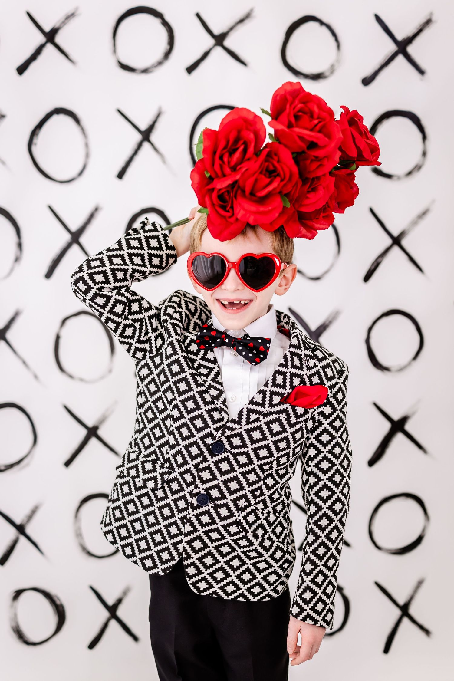 Valentine themed portrait with geometric print jacket, heart sunglasses and red floral headpiece.