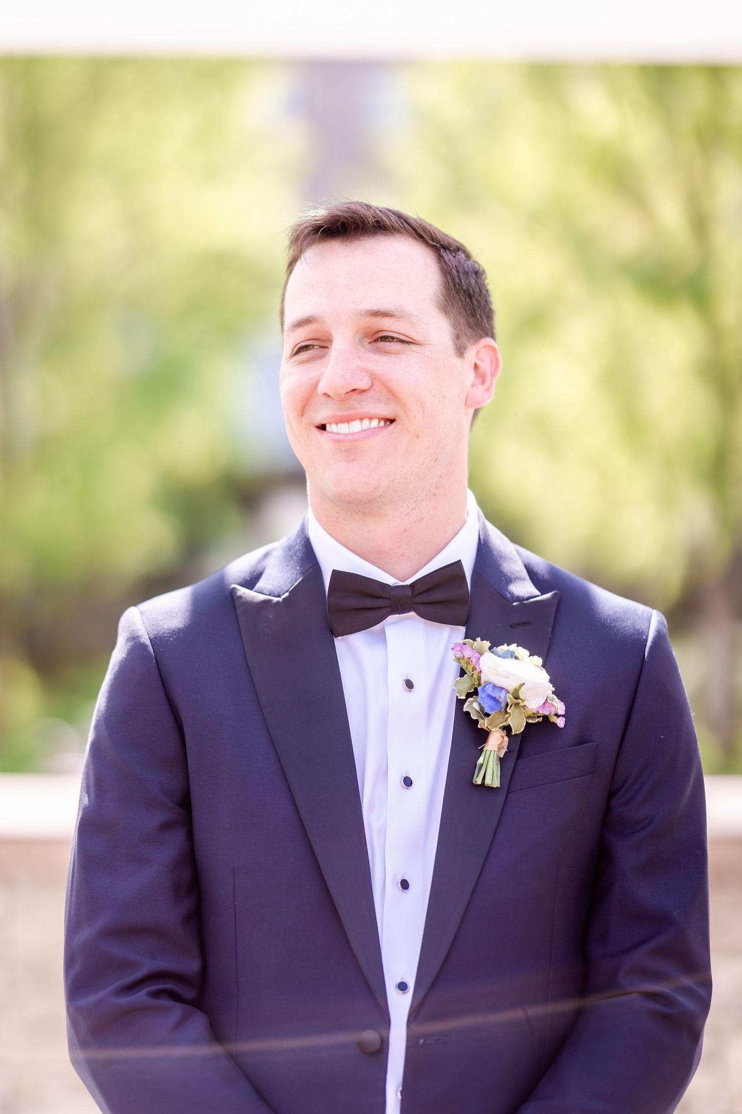 A series of portraits showing a groom in a classic black tuxedo and bowtie smiling outdoors.