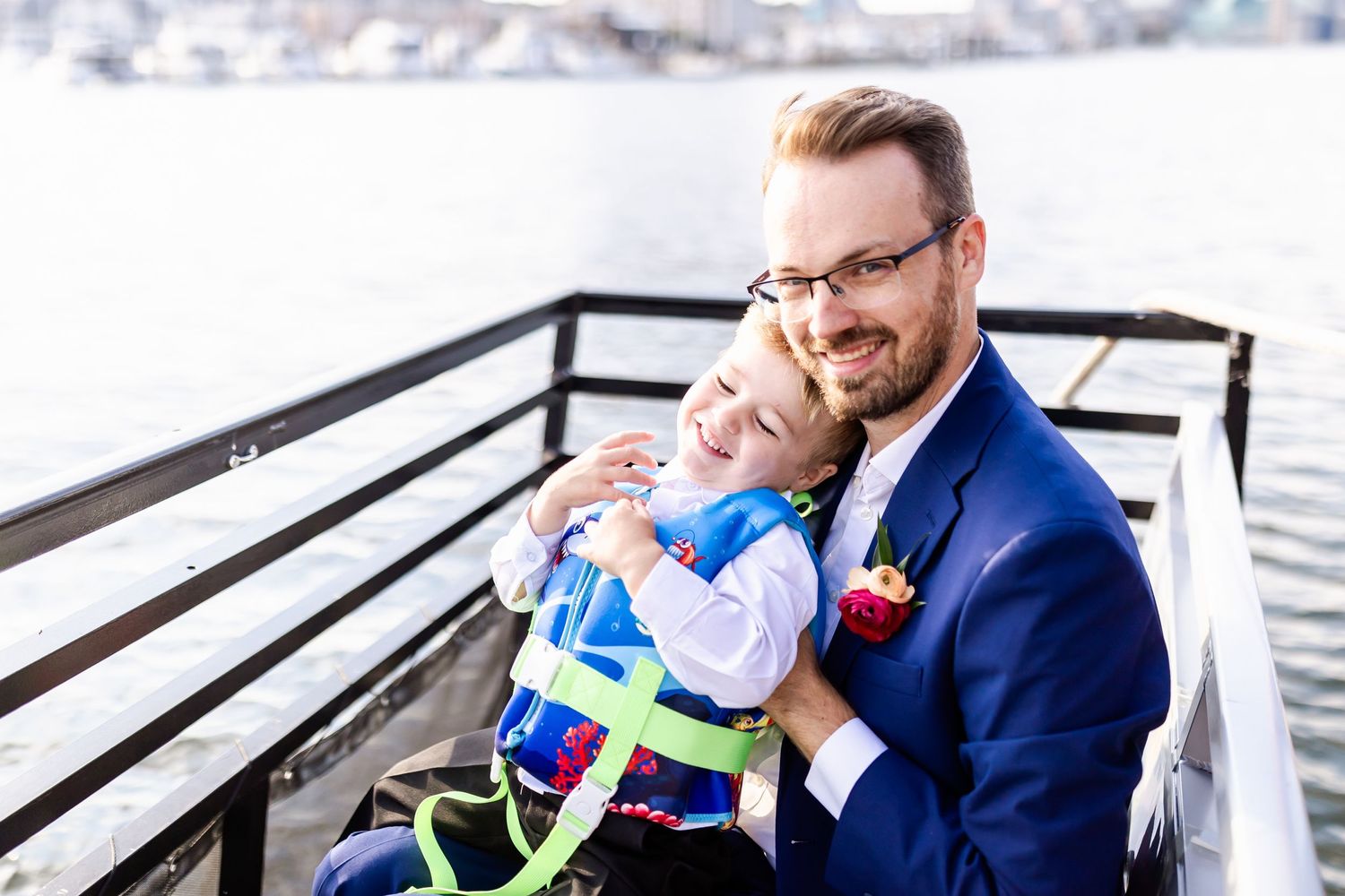 Parent and young child snuggle together on outdoor deck with bright blue winter clothing.