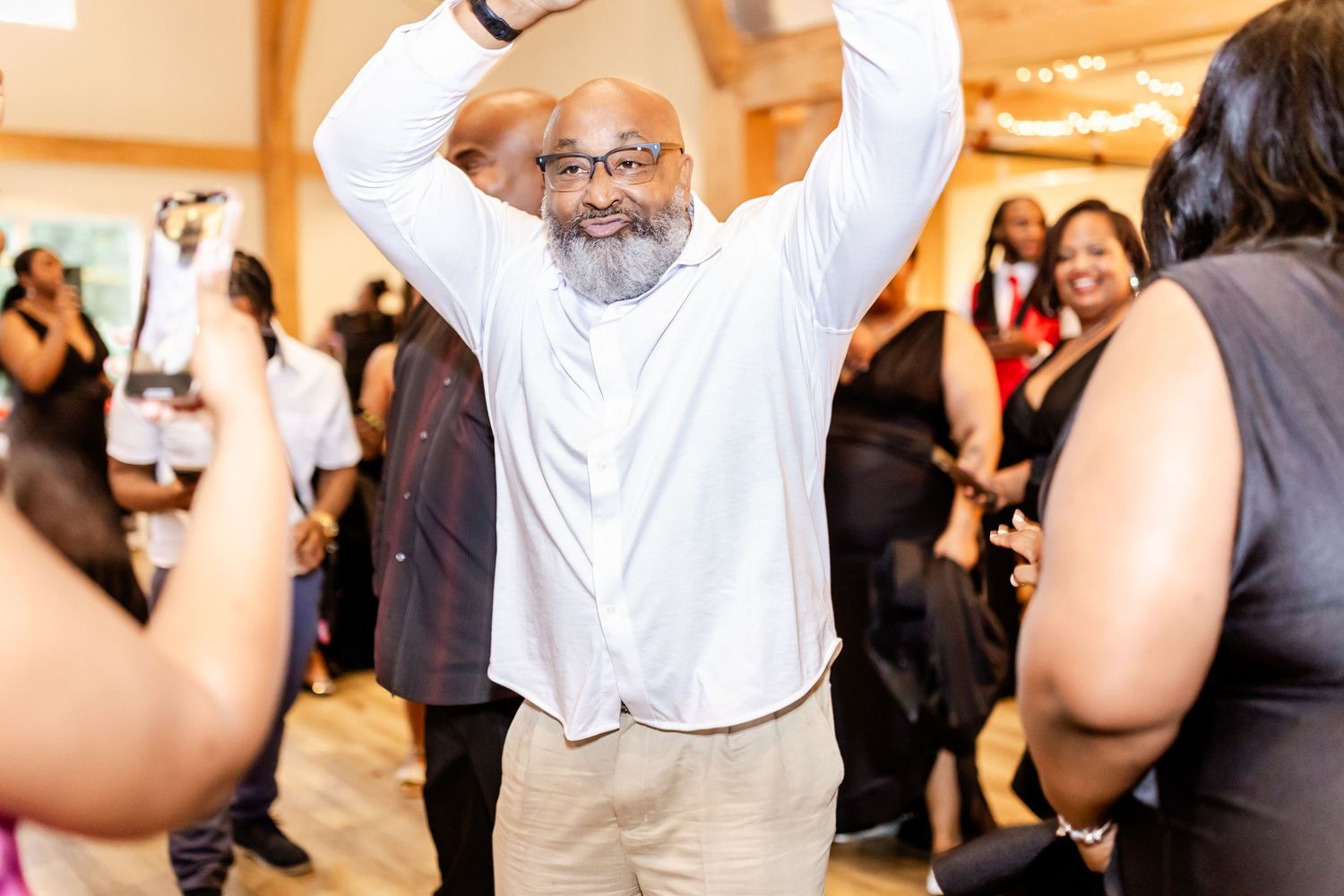 A person dancing joyfully with raised arms at an indoor celebration.