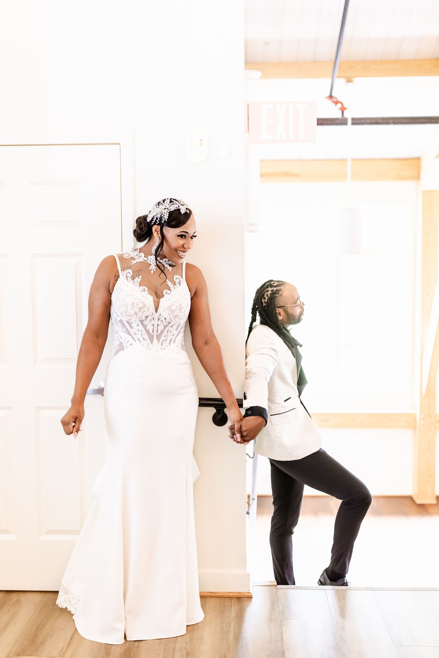A stunning wedding gown with lace details and flowing skirt is showcased in a bright indoor setting.