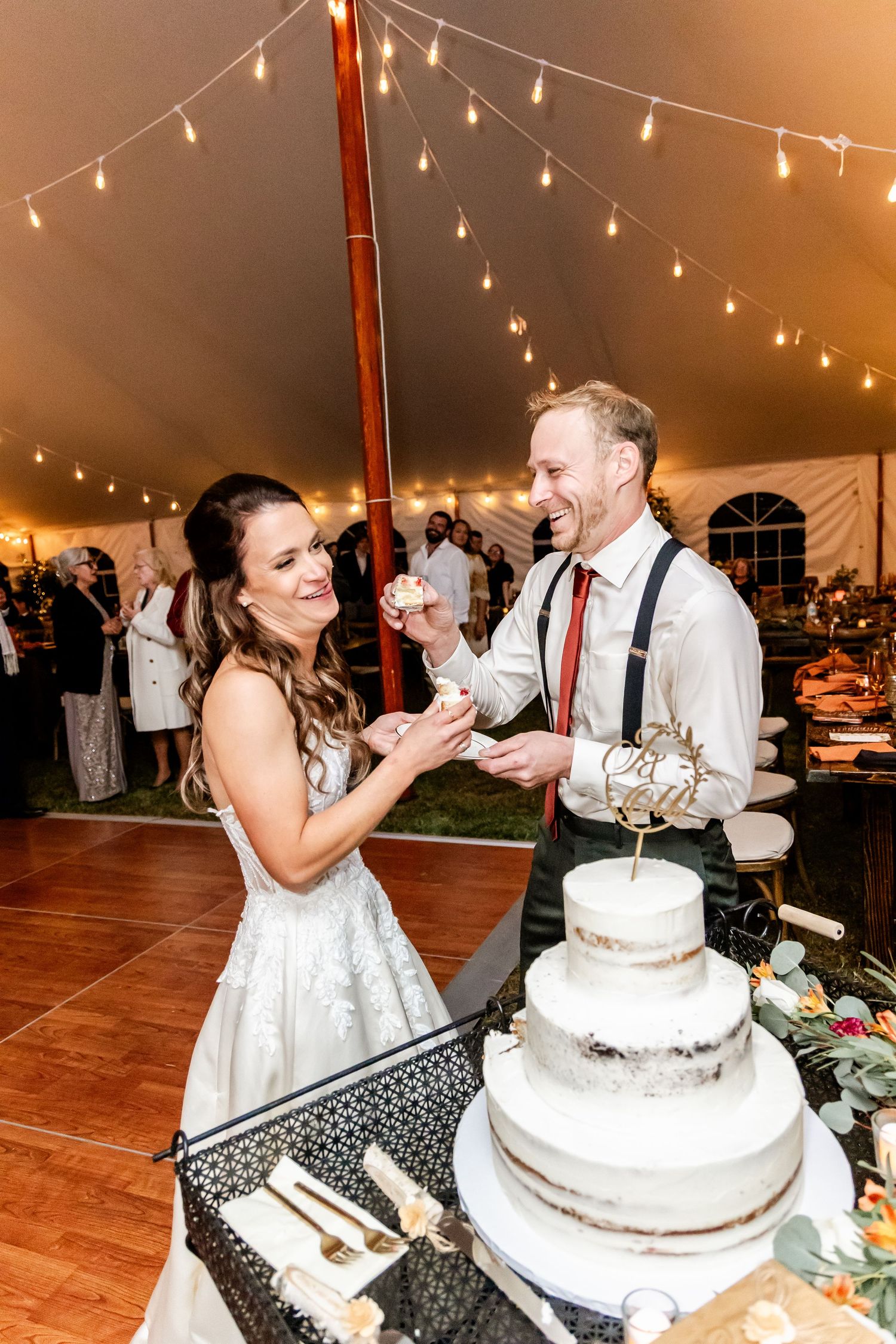 Wedding couple playfully feeding each other cake during traditional cake cutting ceremony.