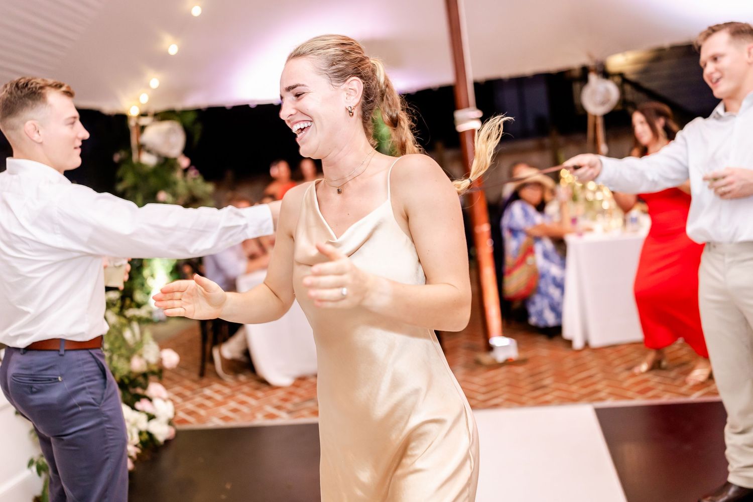 Couples dancing together at an elegant wedding reception with pink lighting and decorative elements.