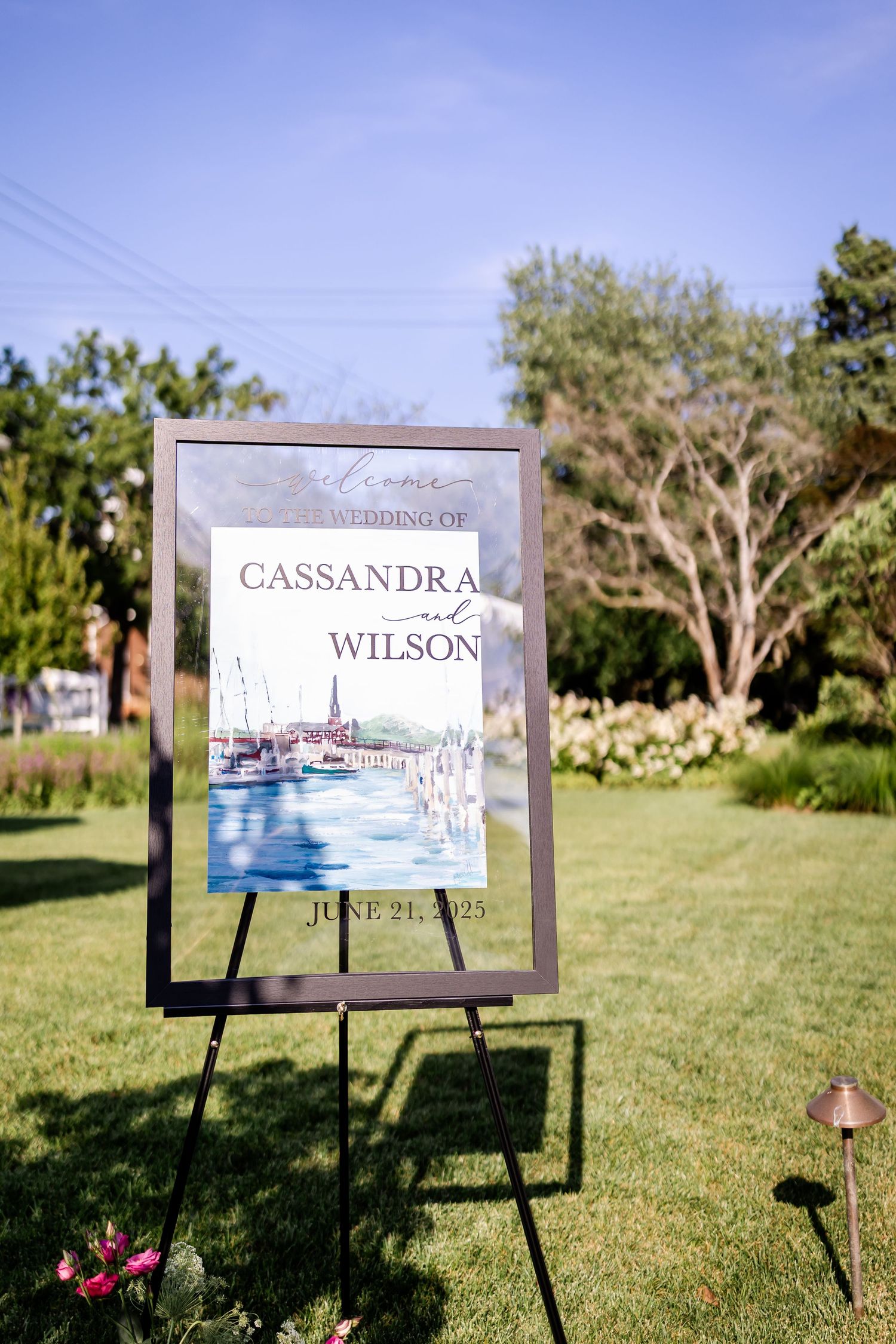 Wedding signage displays featuring nautical artwork on easels set up on a green lawn.