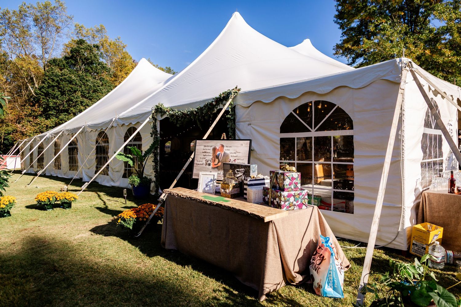 Large white wedding tent set up outdoors with catering tables and autumn decorations.