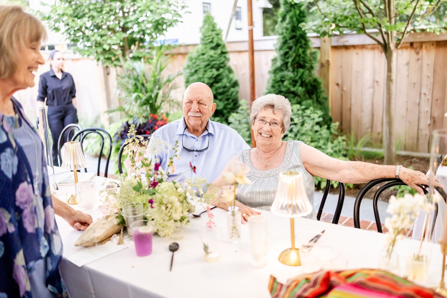 Guests socializing at outdoor tables during a summer garden party celebration.
