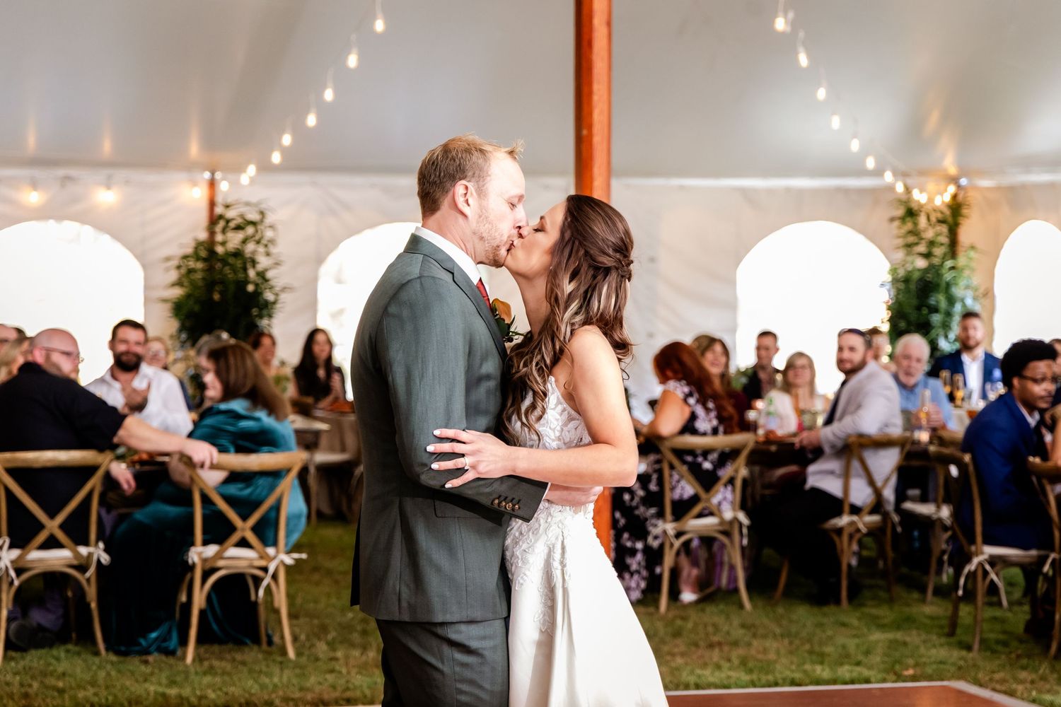 Wedding reception venue decorated with string lights and white tent covering.