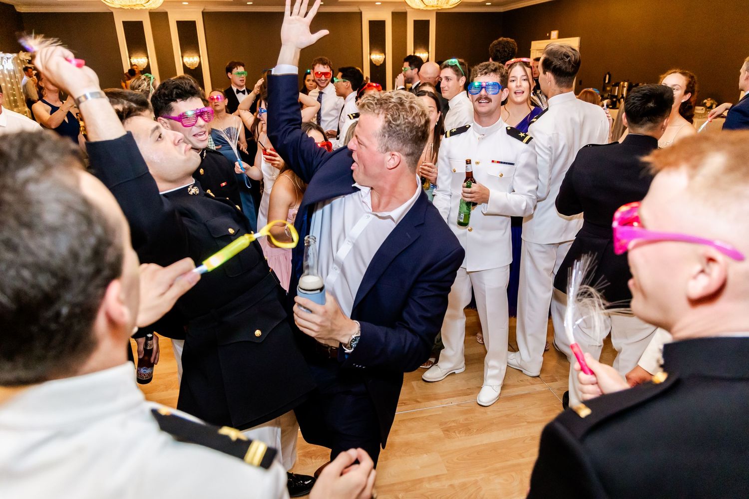 Lively reception dance floor with guests celebrating in a warmly lit ballroom.