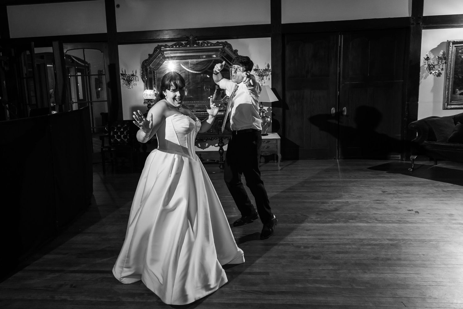 Couple sharing first dance in black and white photo at elegant indoor wedding reception.