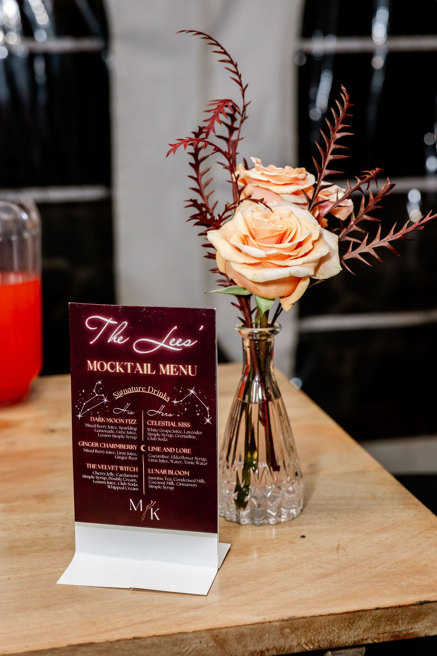 Elegant mocktail menu display with peach rose centerpiece in crystal vase.