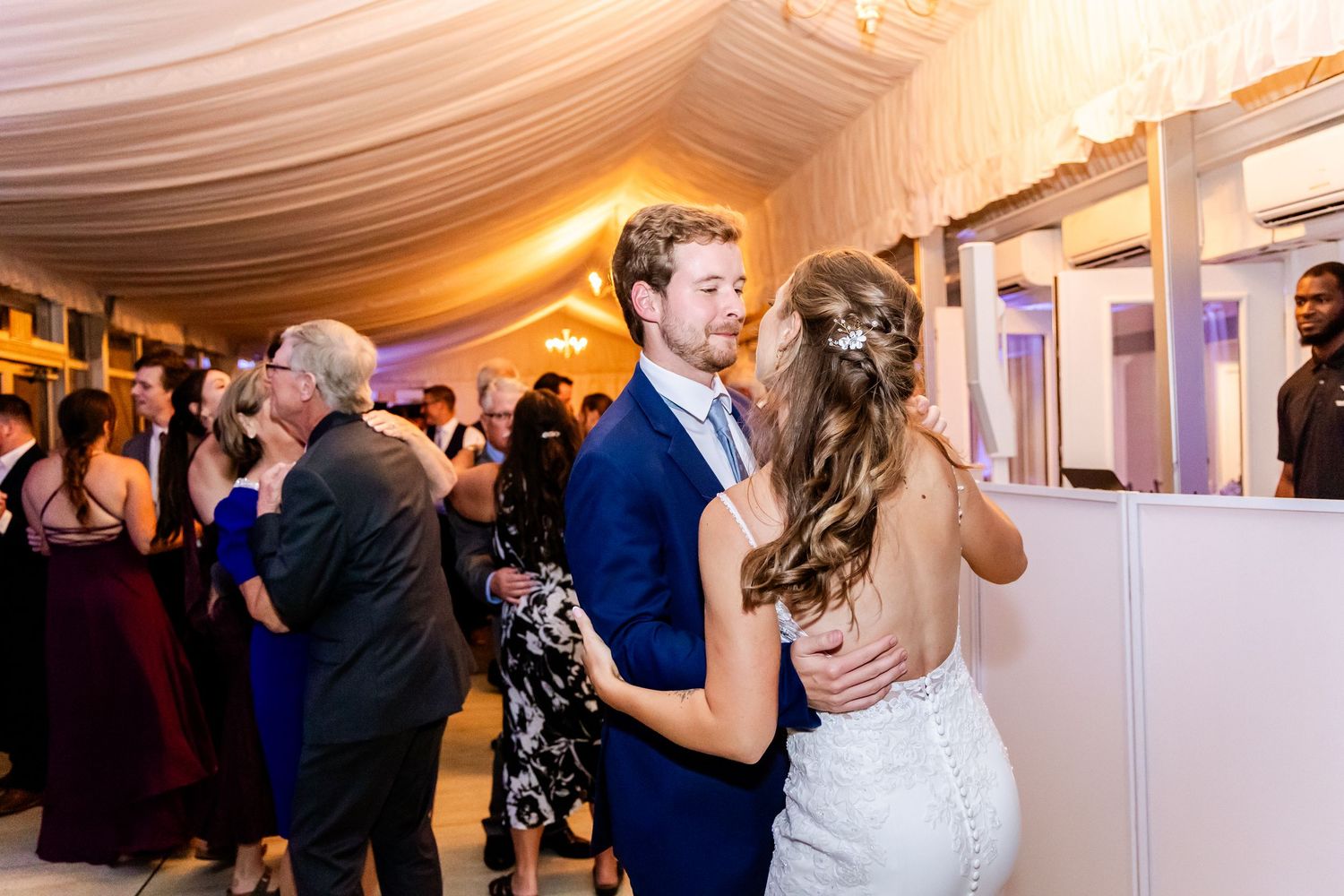 Couple dances together under draped fabric ceiling at their wedding reception.