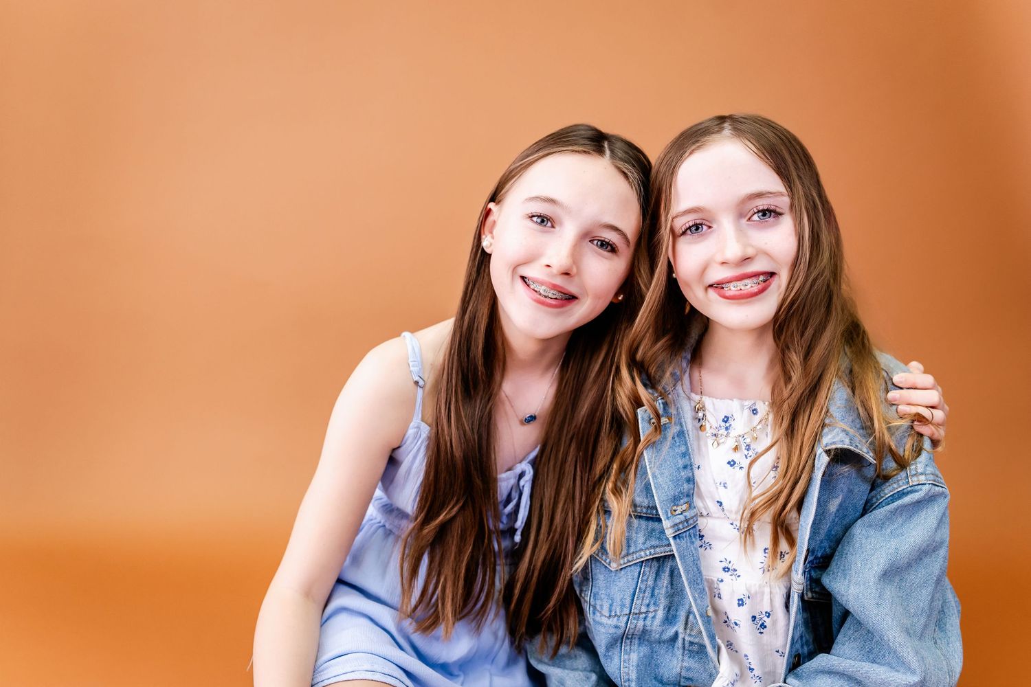 Two people wearing denim jackets smile together against an orange background in a series of casual photo poses.