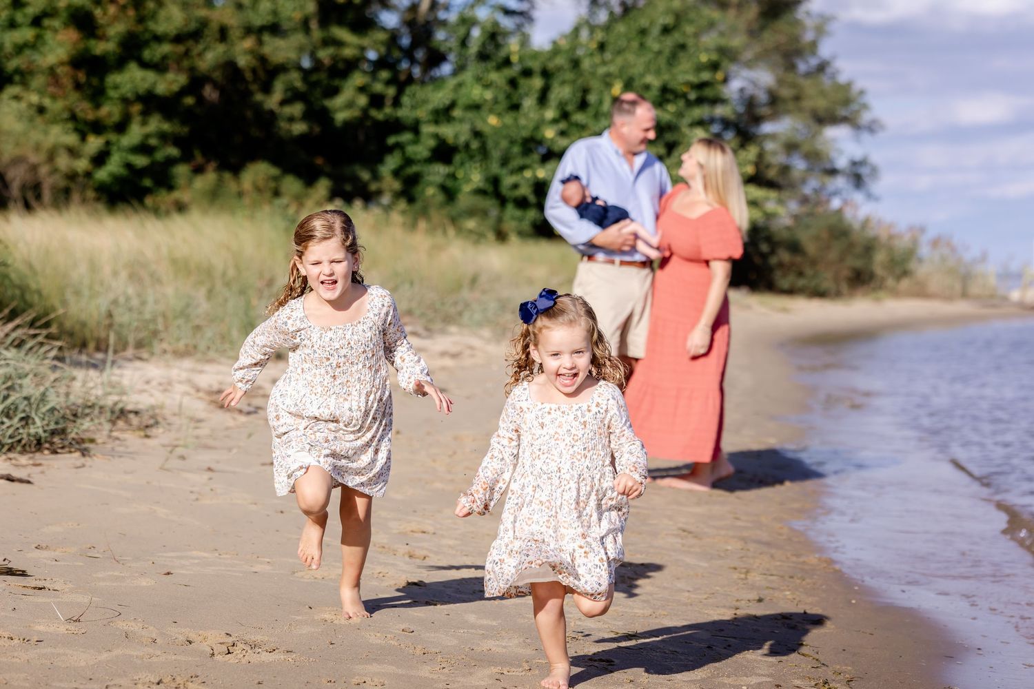 Children playing and running along a sandy beach shoreline on a sunny summer day.