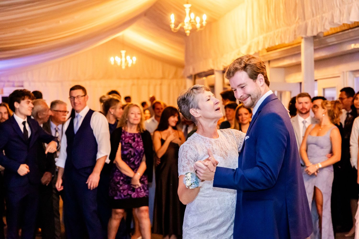 Guests enjoying a lively dance floor celebration at an indoor wedding reception with elegant draping.