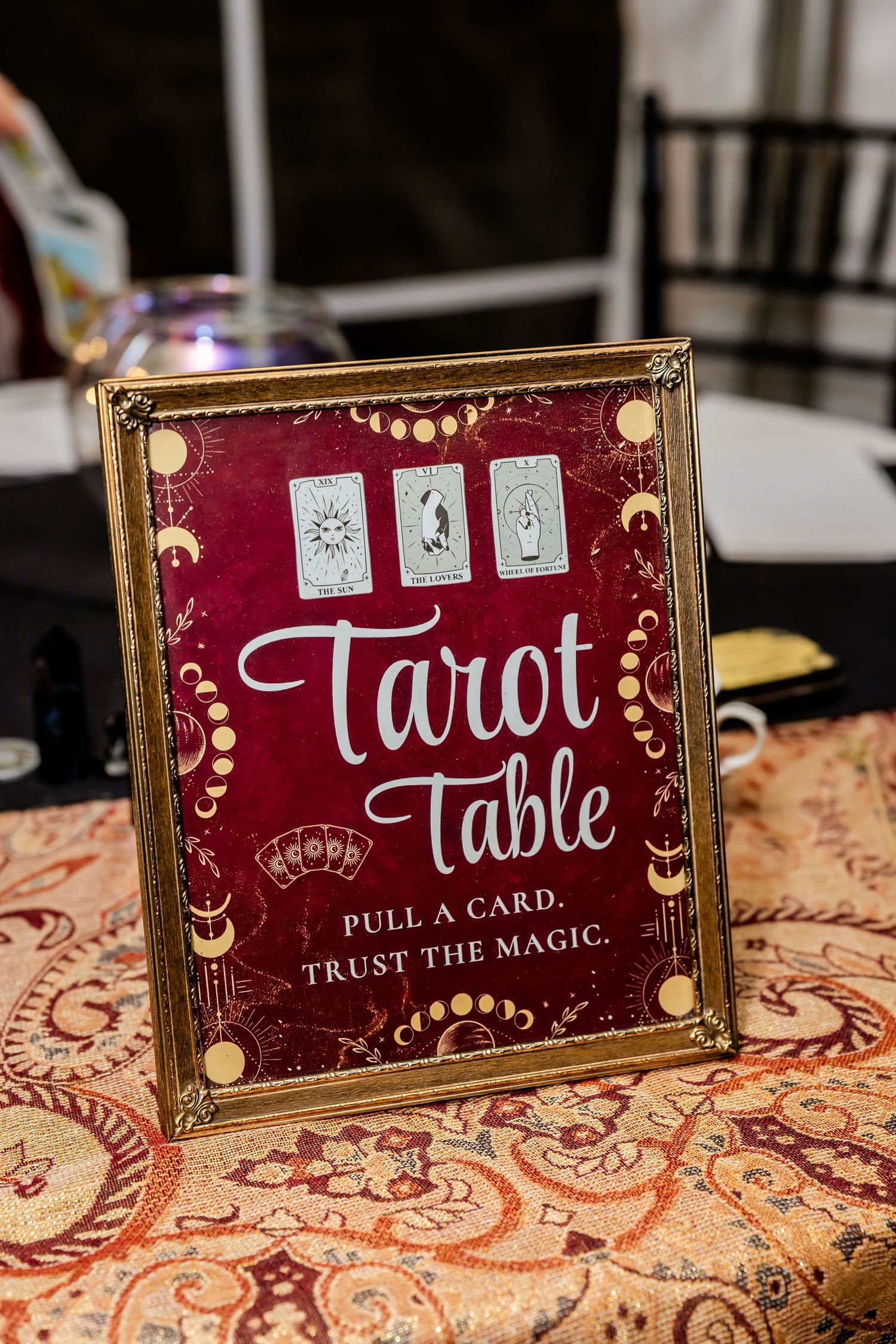 Decorative gold-framed Tarot Table signs on a patterned tablecloth at an event.