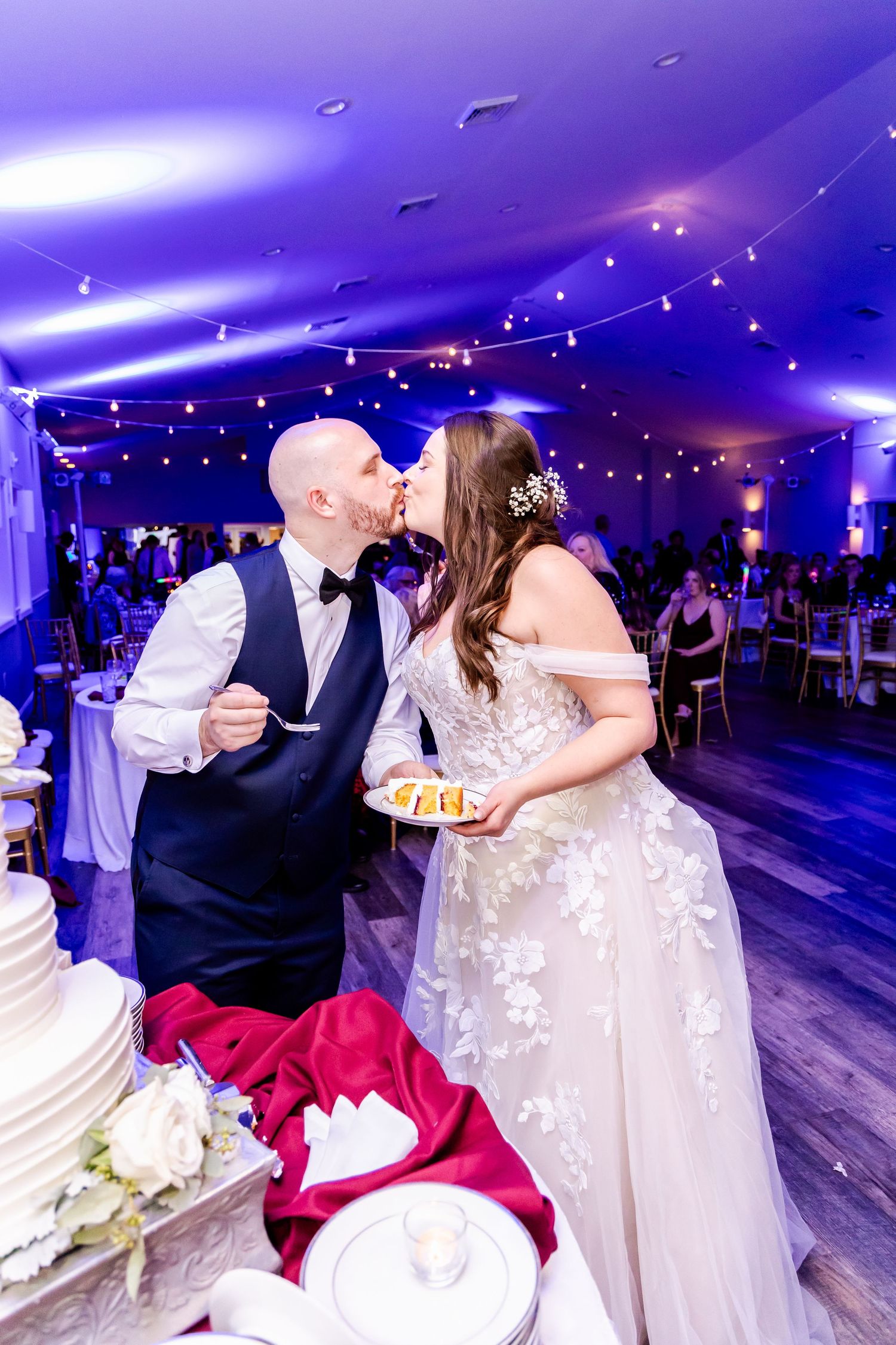 A romantic dip and kiss sequence between newlyweds on a purple-lit dance floor during their wedding reception.