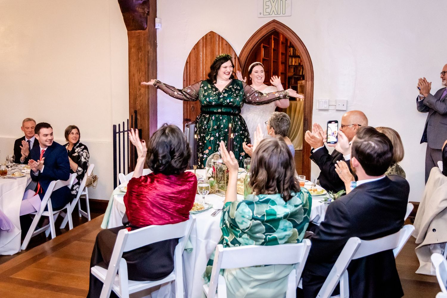 Wedding celebration in a chapel with guests seated in white chairs watching a joyful performance.