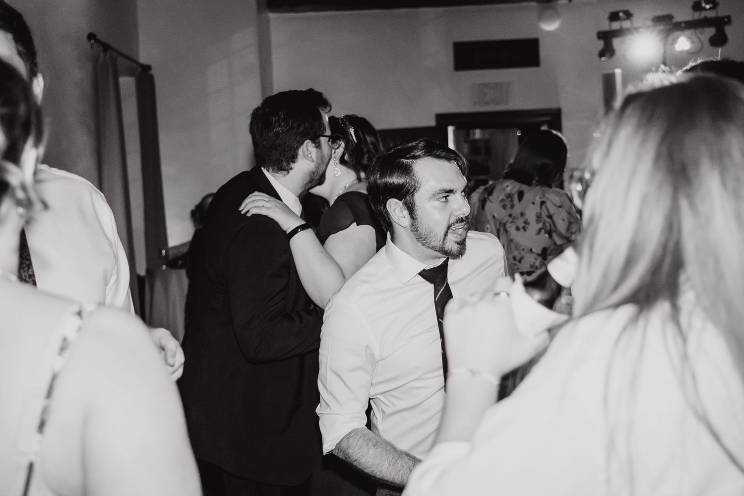 Black and white photo of people dancing at a lively wedding reception.