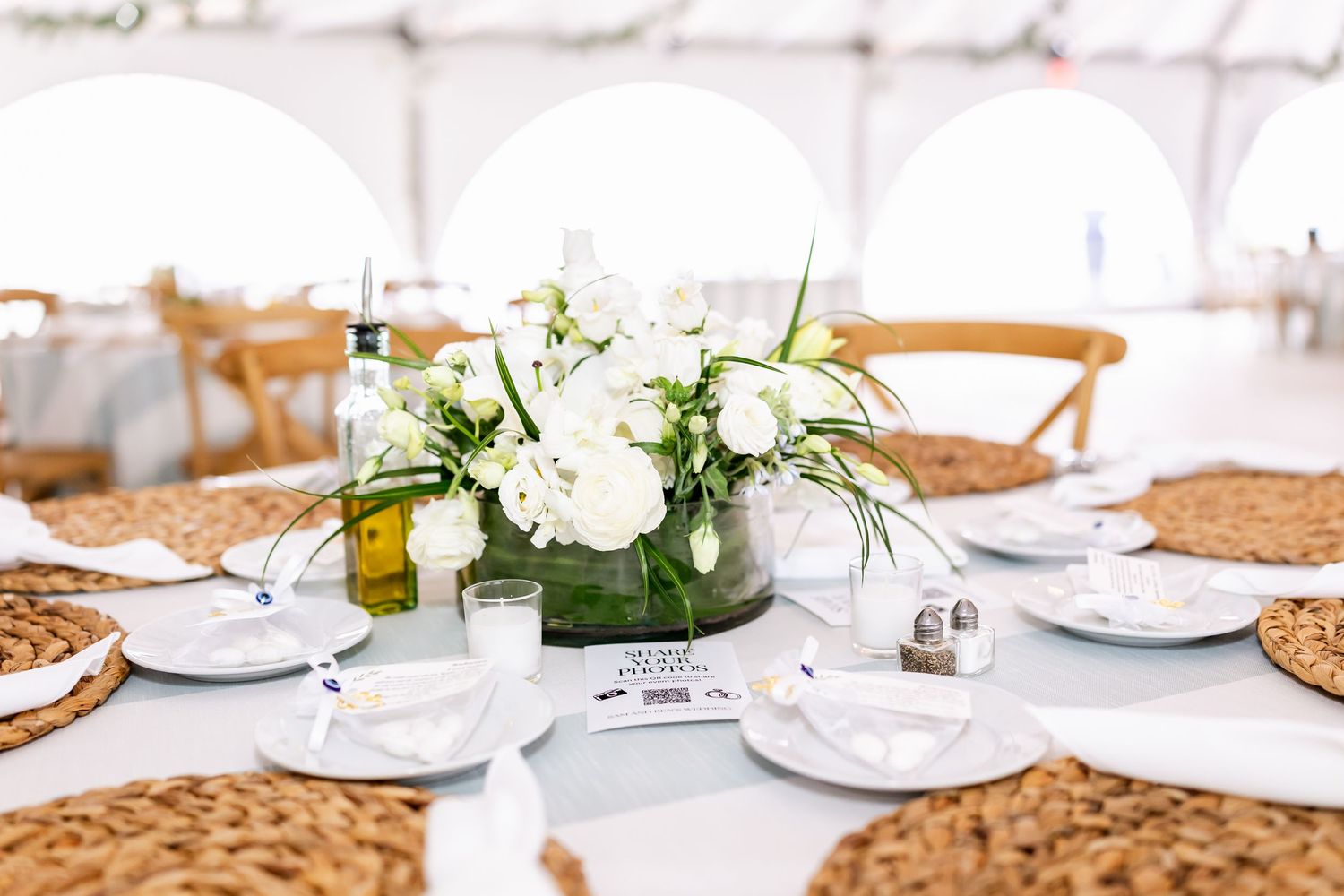 Elegant white table settings with woven placemats at wedding reception.
