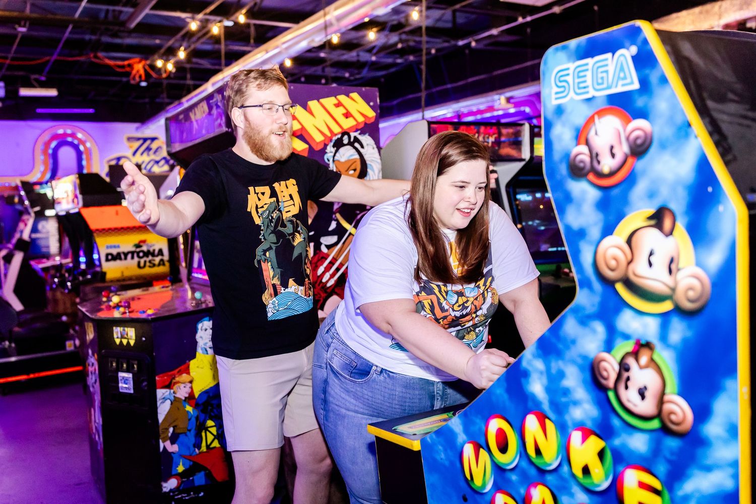 Players having fun at a vibrant arcade with glowing Monkey Ball game machine in foreground.