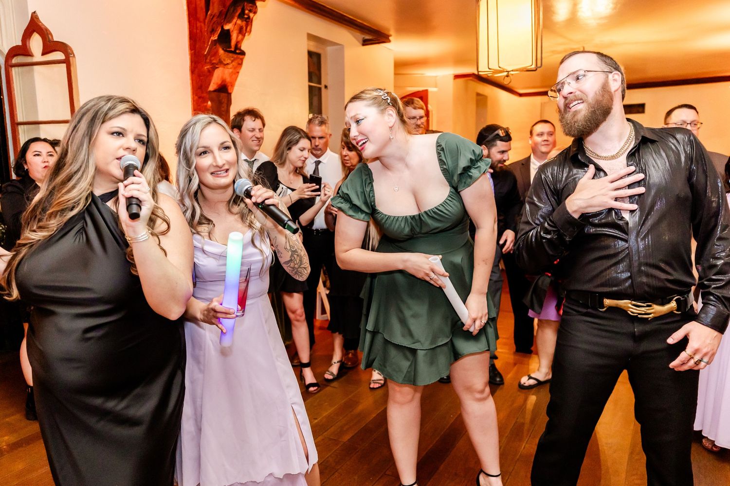 Group of party guests singing and dancing together at a festive indoor celebration.