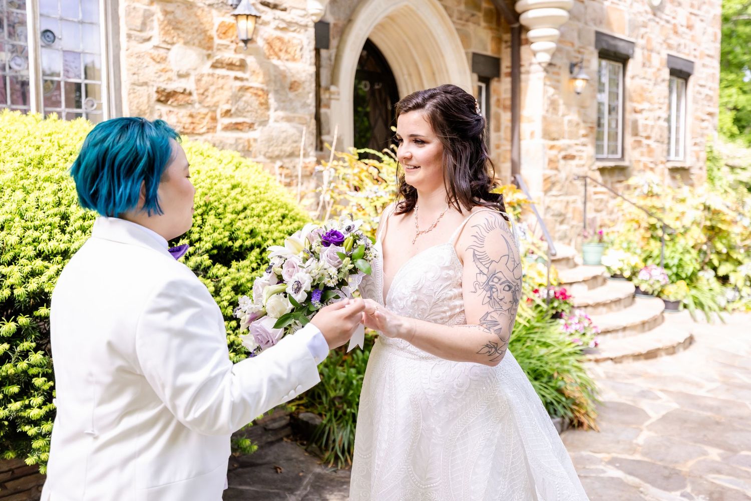 Couple exchanging flowers during wedding first look at stone castle entrance.