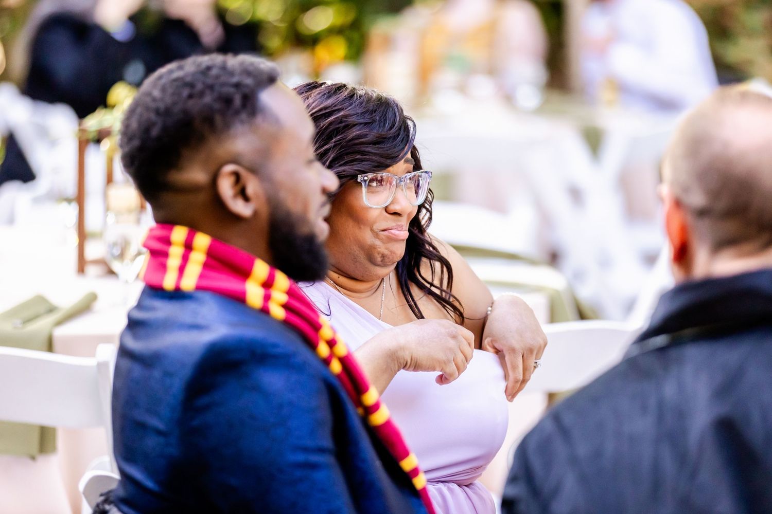 Wedding guests engaged in lively conversation at an outdoor reception.