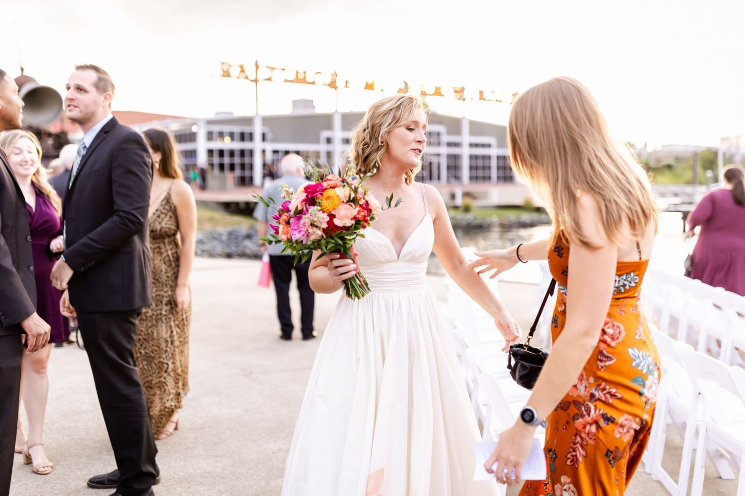 Wedding celebration on a pier with guests and bridal party gathering outdoors.