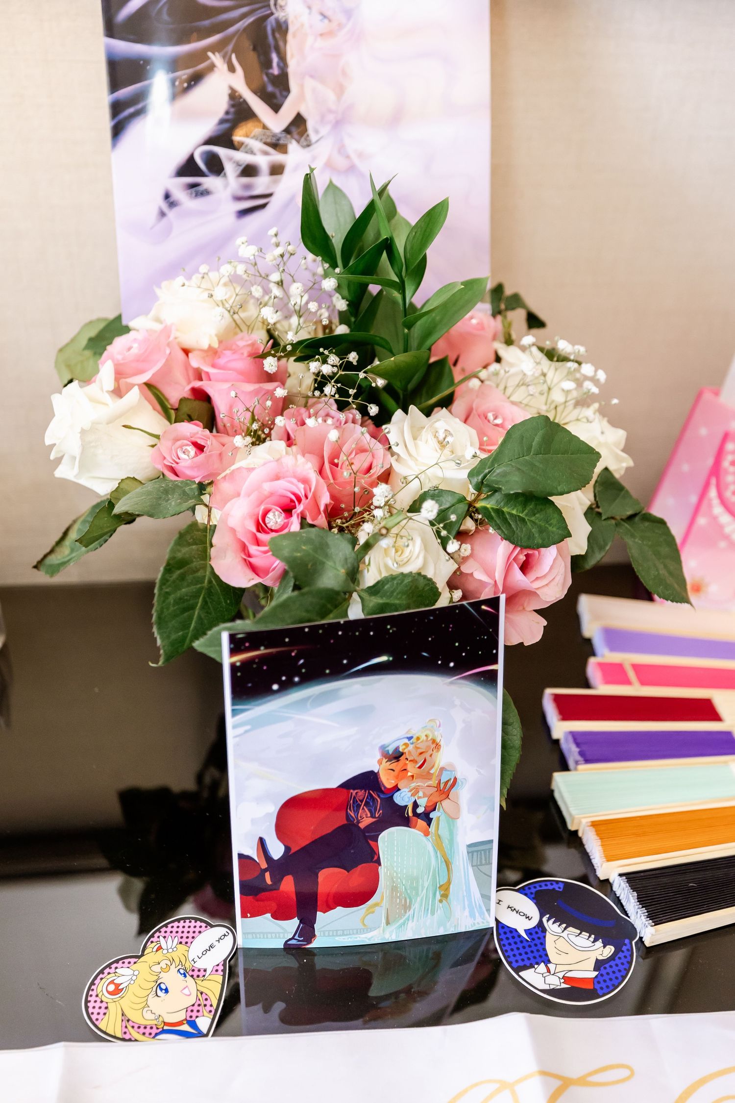 Pink floral arrangement with anime art display and color swatches for wedding planning.