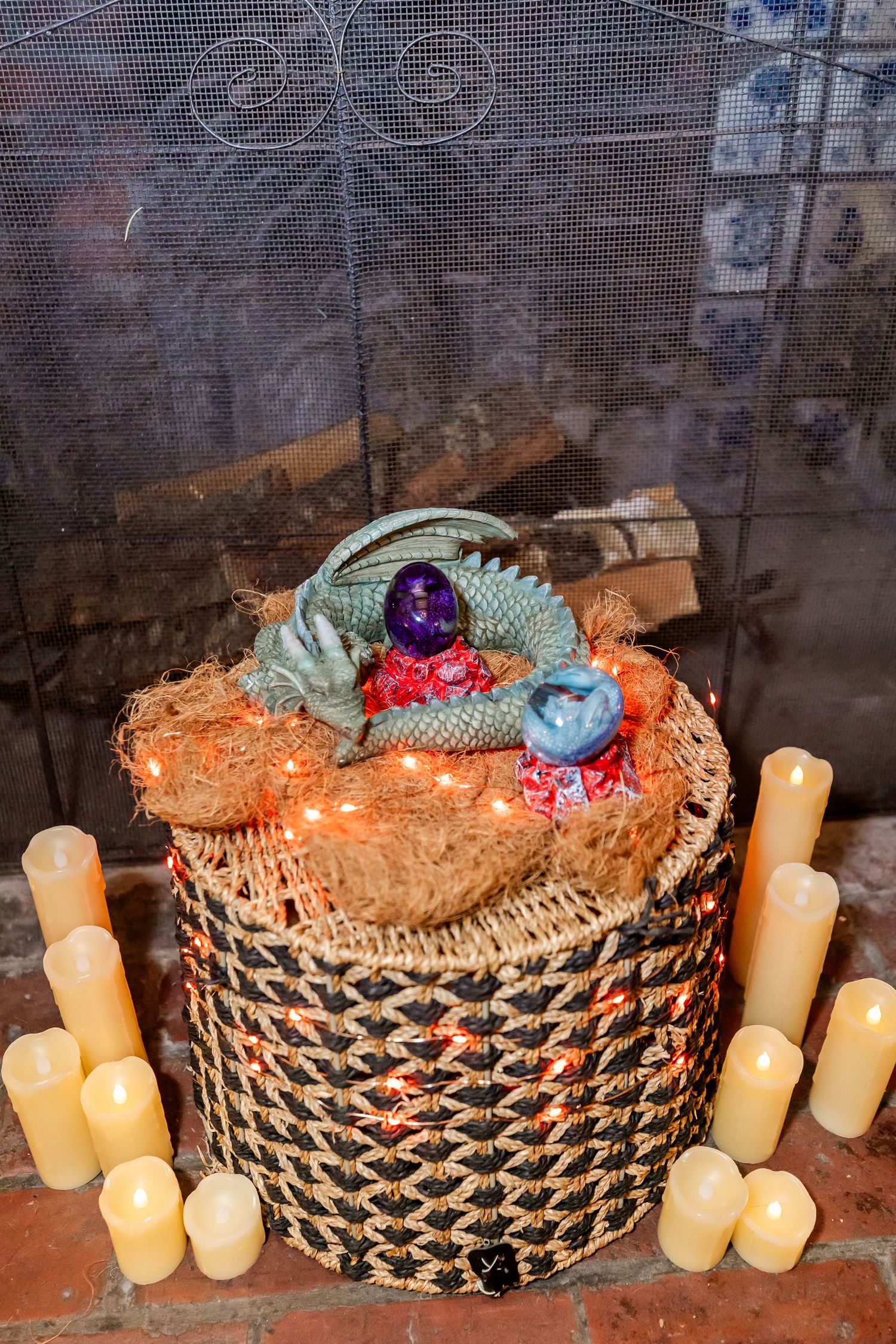 Decorative basket with dragon eggs and candles arranged in fireplace setting.