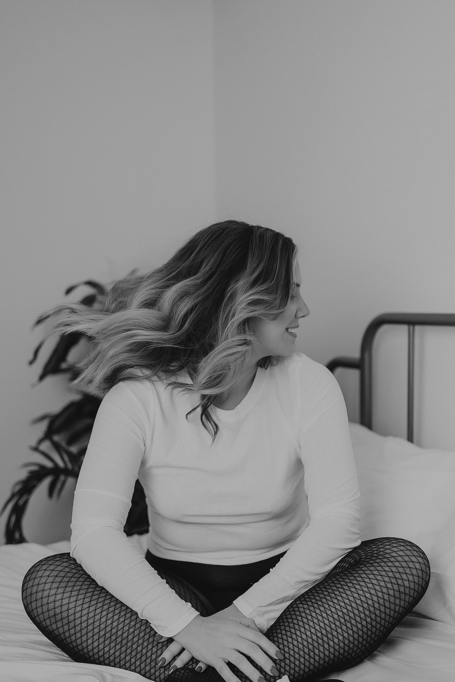 Black and white boudoir photos on bed with natural window light.