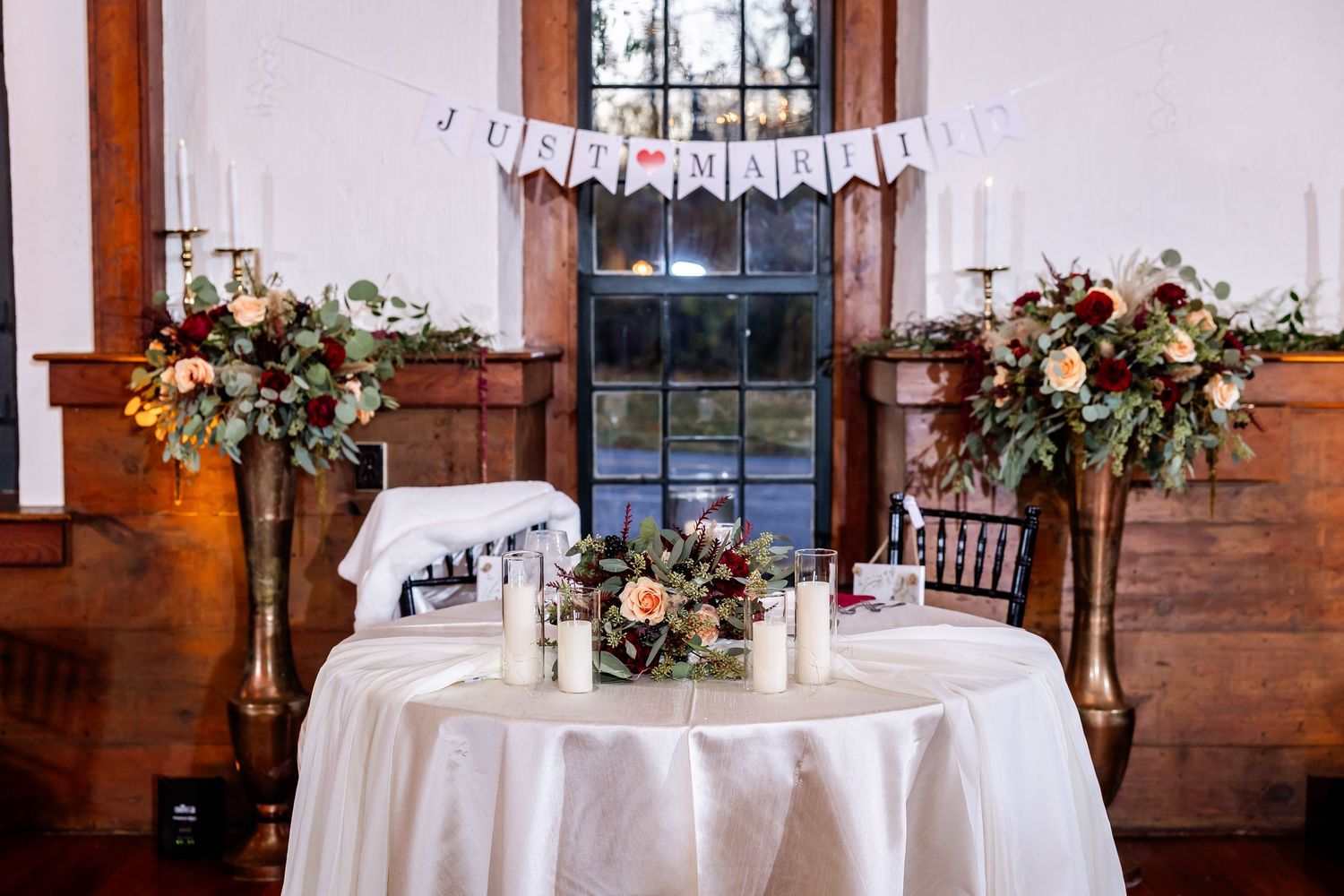 An elegant indoor wedding reception venue with floral centerpieces and white table settings.