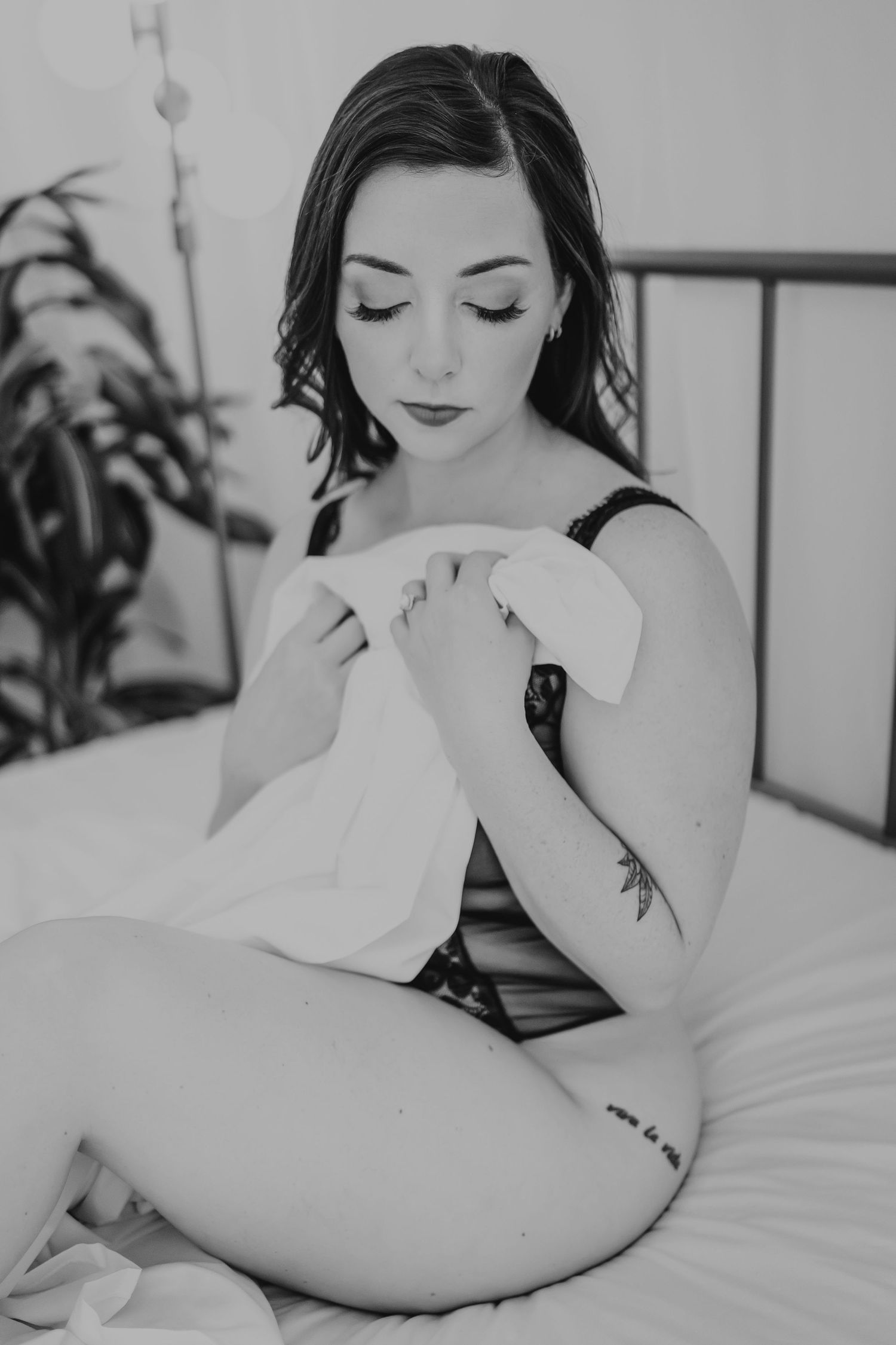 Black and white boudoir photo series showing intimate bedroom poses with soft lighting and white bedding.