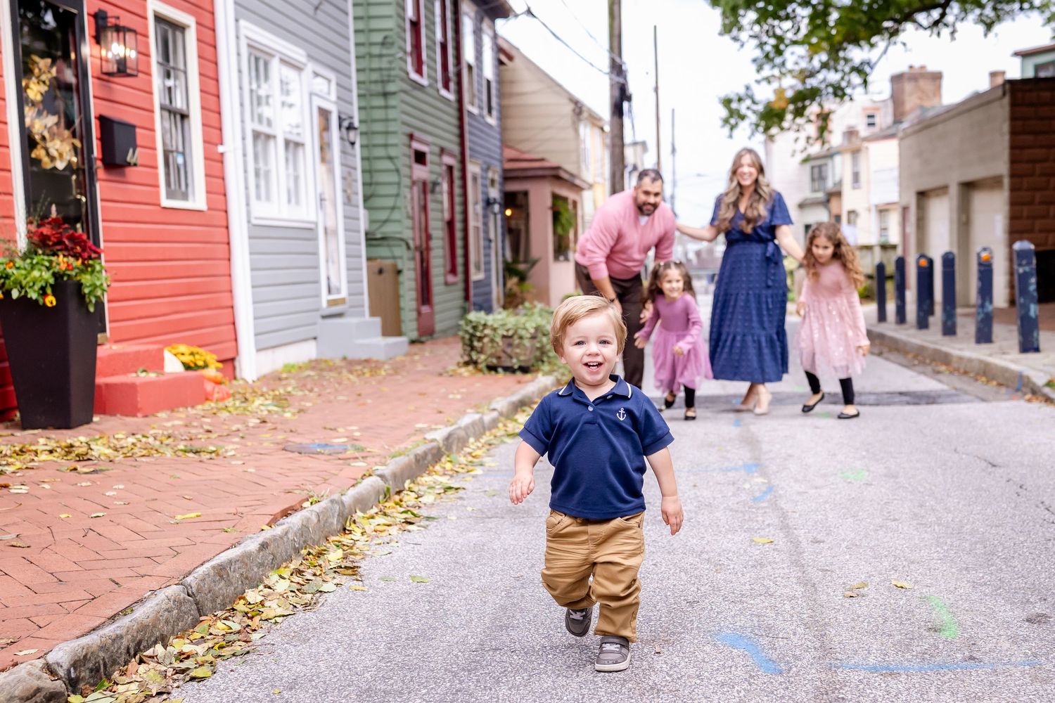Group walking down a cobblestone street lined with colorful historic buildings.