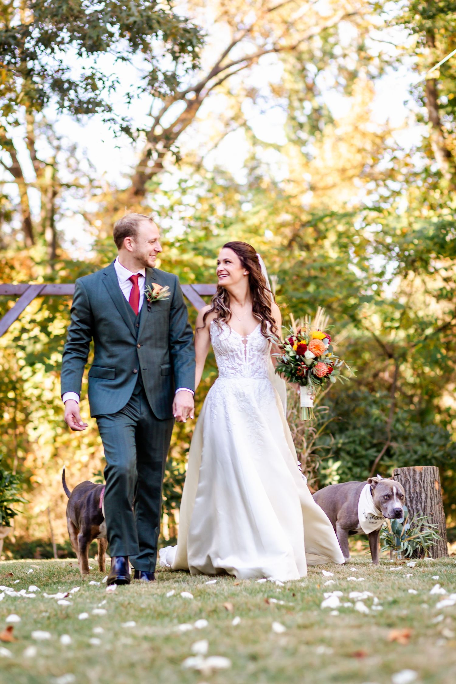 Couple walks together on leaf-covered ground during autumn wedding photoshoot.