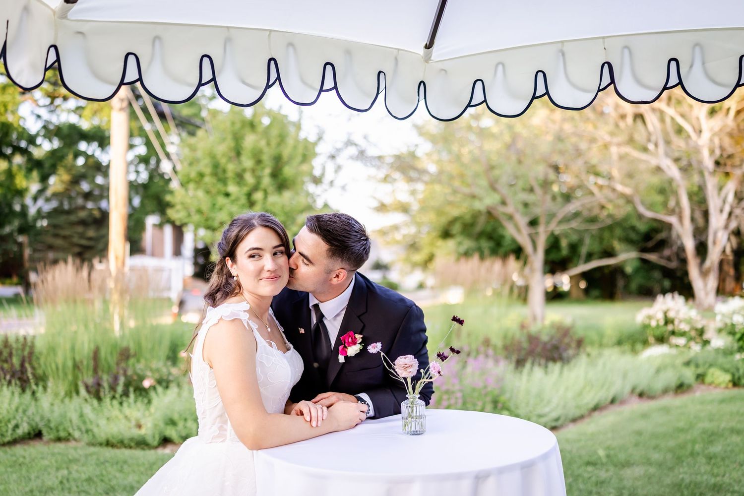Romantic outdoor seating area with white parasols and garden views at a wedding venue.