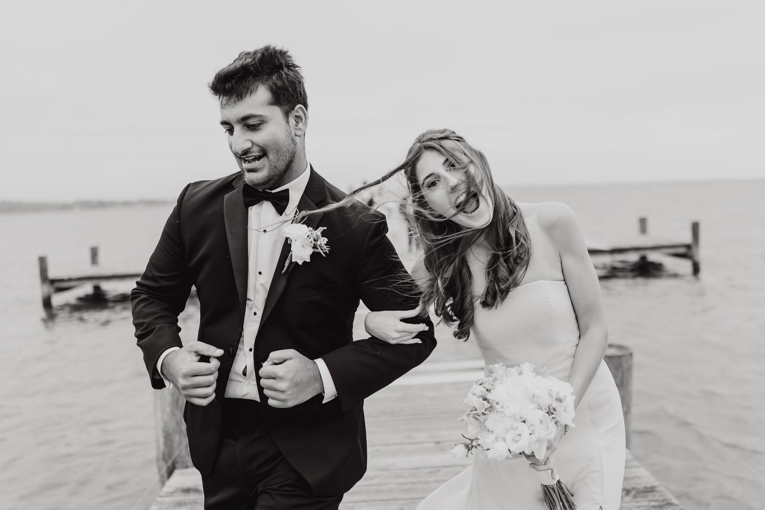 Black and white wedding portraits showing candid moments by the water.