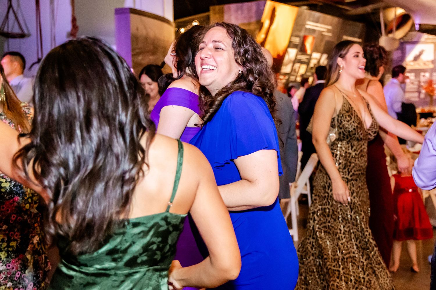 Guests dancing and celebrating on a lively reception dance floor with colorful lighting.