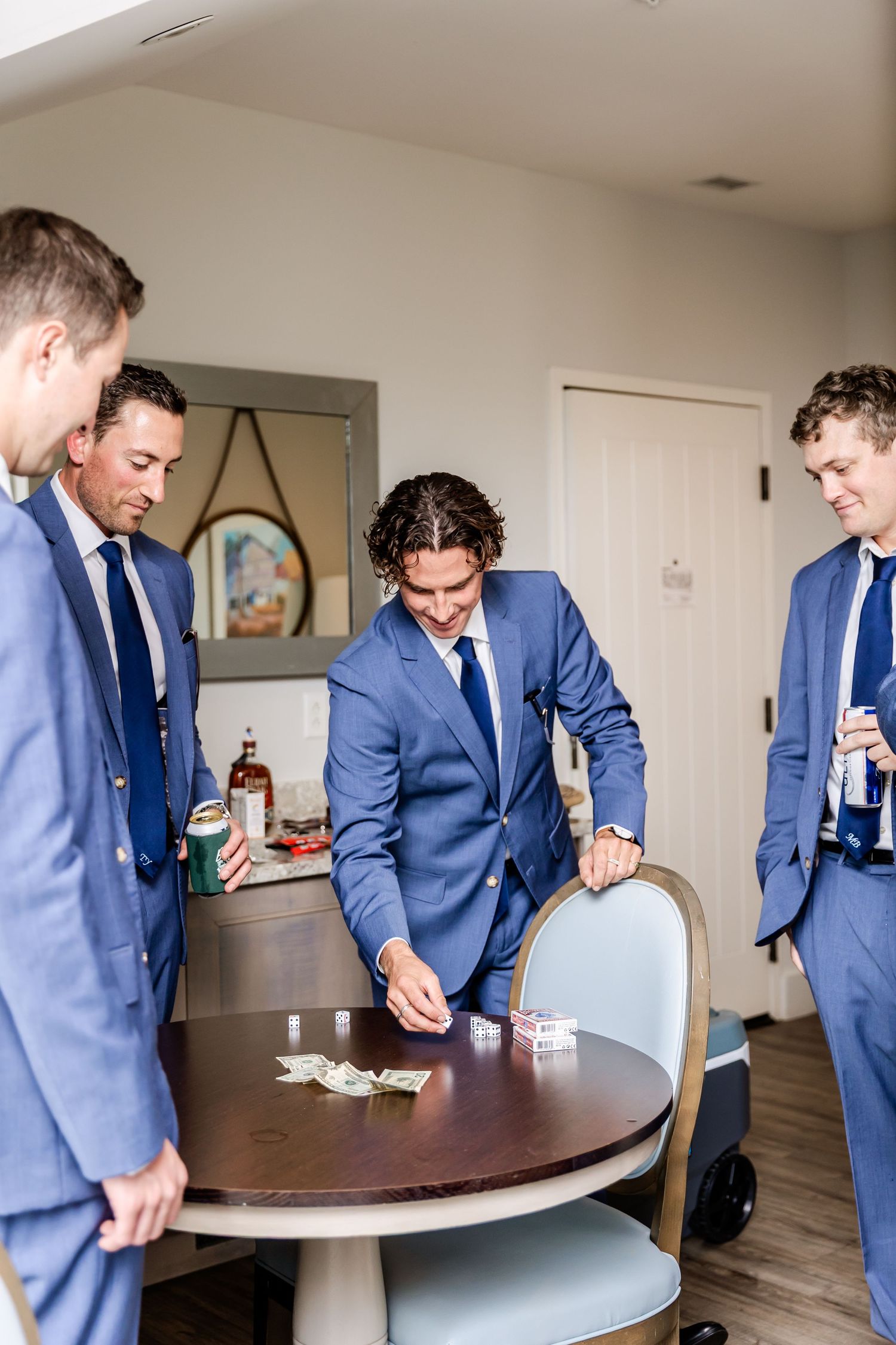 Groomsmen in blue suits gather around a dark table during wedding preparations.
