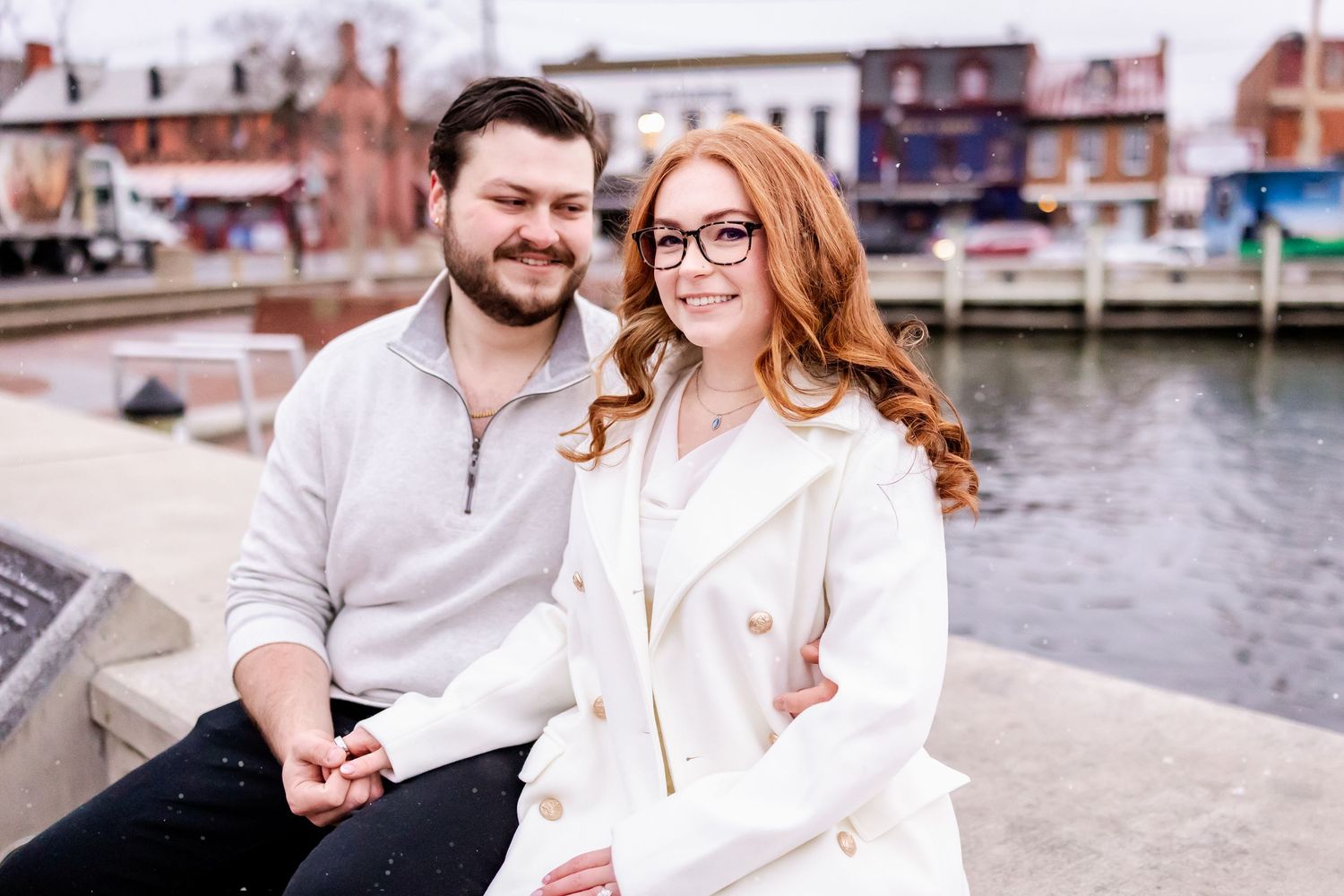 A couple shares joyful moments together along a waterfront boardwalk on a cloudy day.